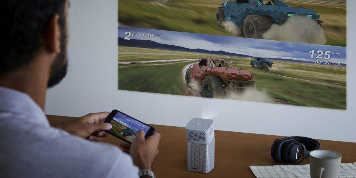 A man playing video games with a  smartphone and a projector