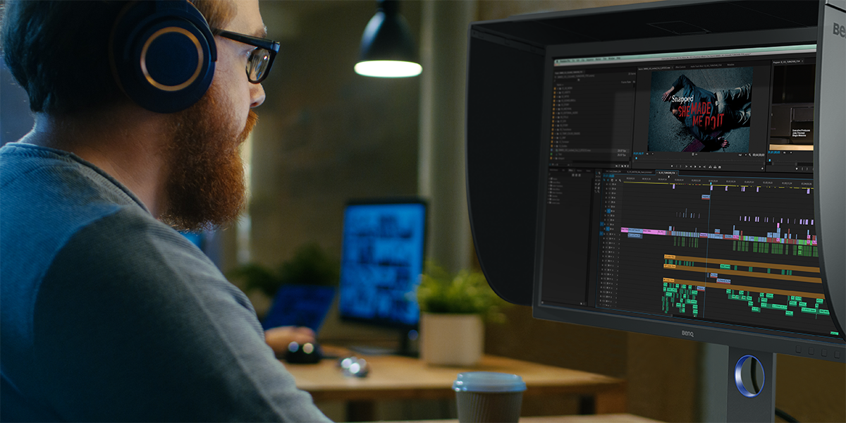 Un esperto di video seduto davanti a un monitor professionale con il flusso di lavoro di editing 