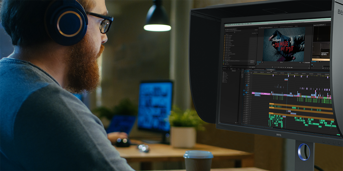 Un experto en vídeo sentado frente a un monitor profesional en su flujo de trabajo de edición 