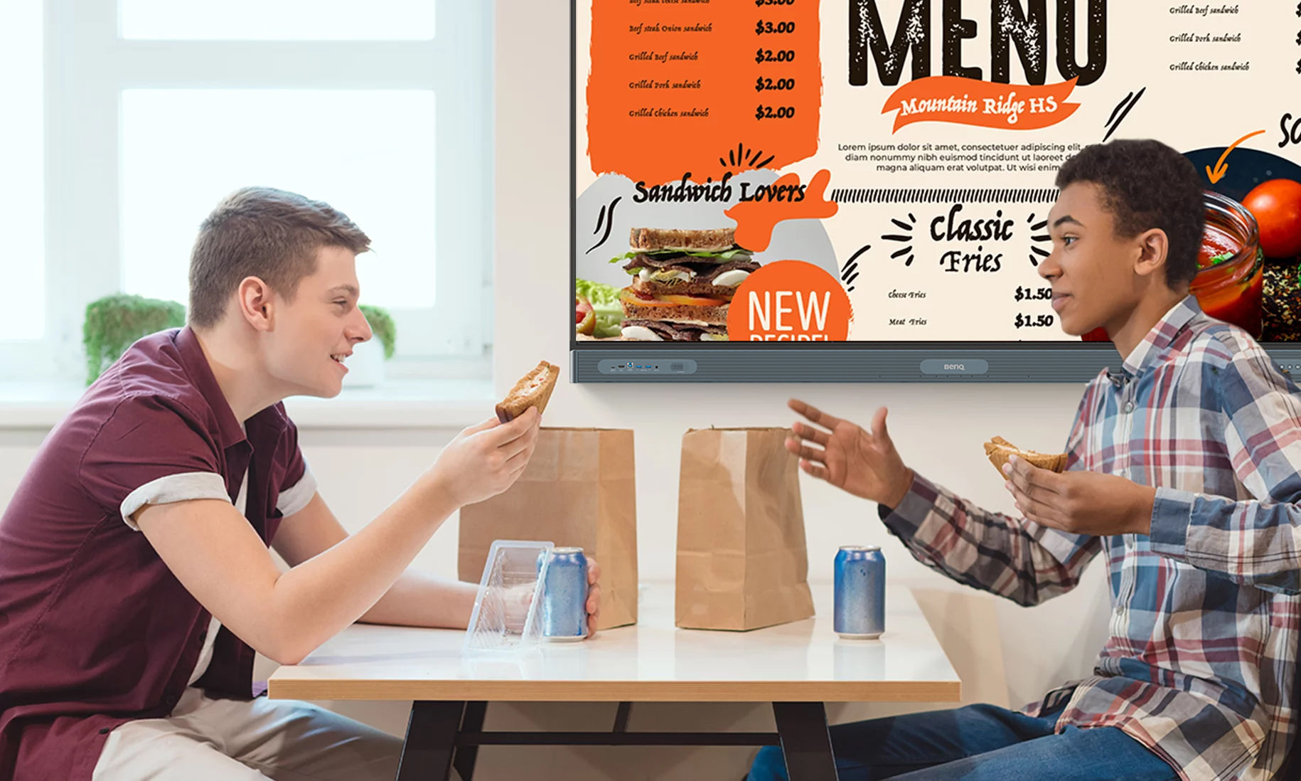 Two students having lunch together in cafeteria in front of digital signage display showing menu