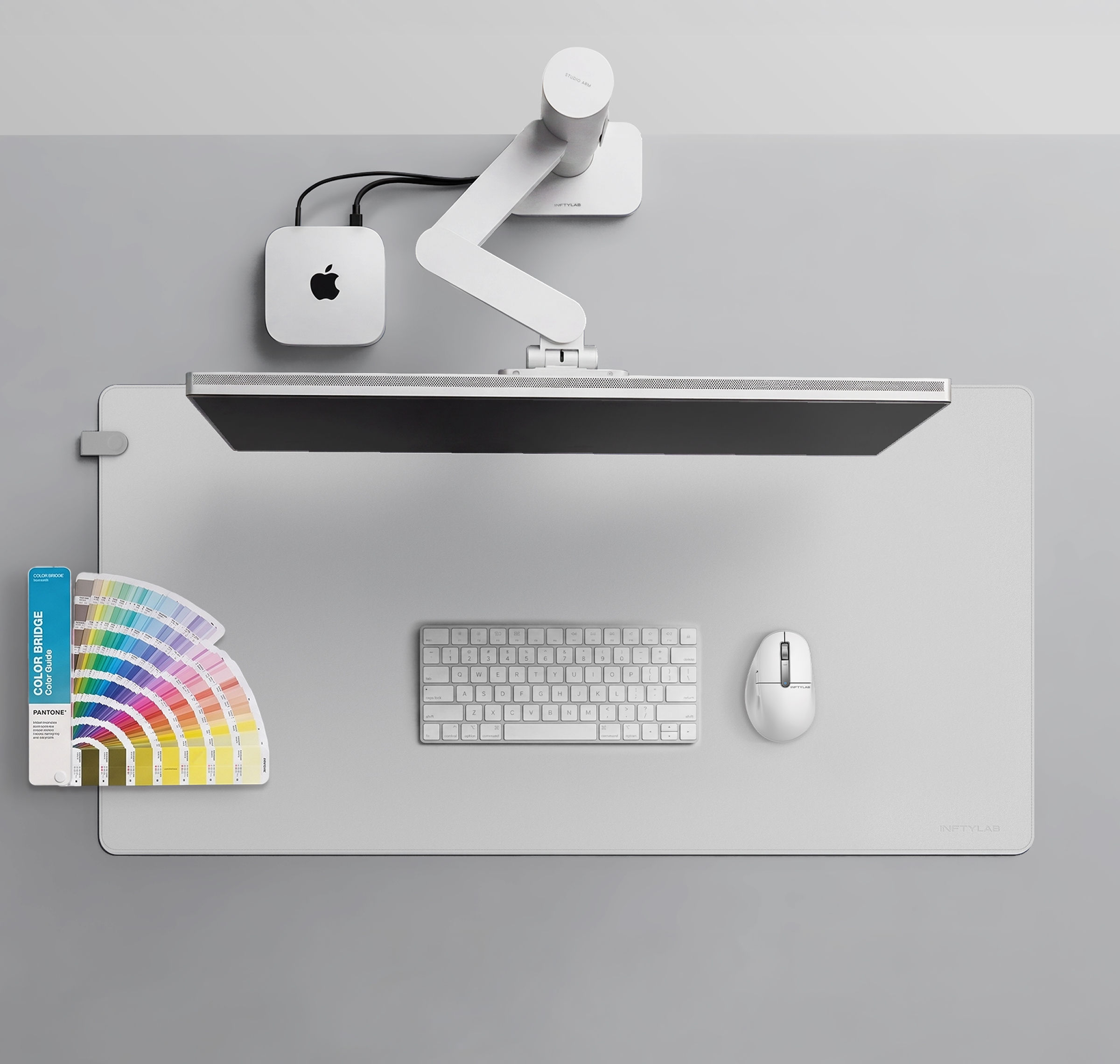 A minimalist Apple workspace displaying INFTYLAB Studio Arm, M Mouse, and Flow Desk Mat integrated with Mac mini, Studio Display, and MacBook, showcasing design consistency across the ecosystem.
