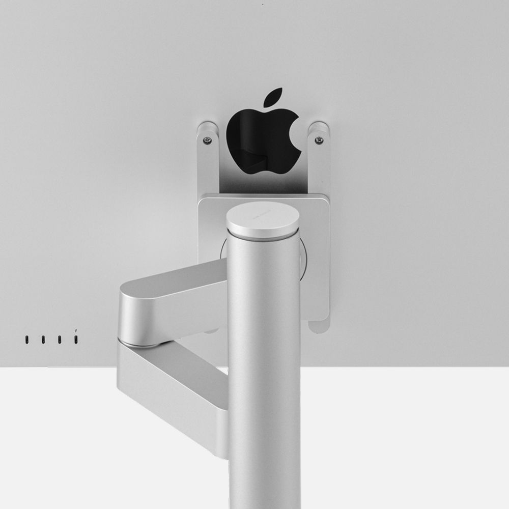 Studio Arm supporting a Studio Display, showing the vertical mounting structure and cable routing through the base, demonstrating design compatibility with Apple products.