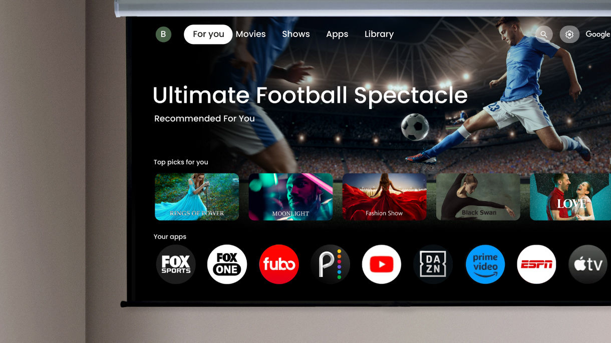 BenQ home theater projector with built-in Google TV showing a sports streaming interface with apps like FOX Sports for world football matches.