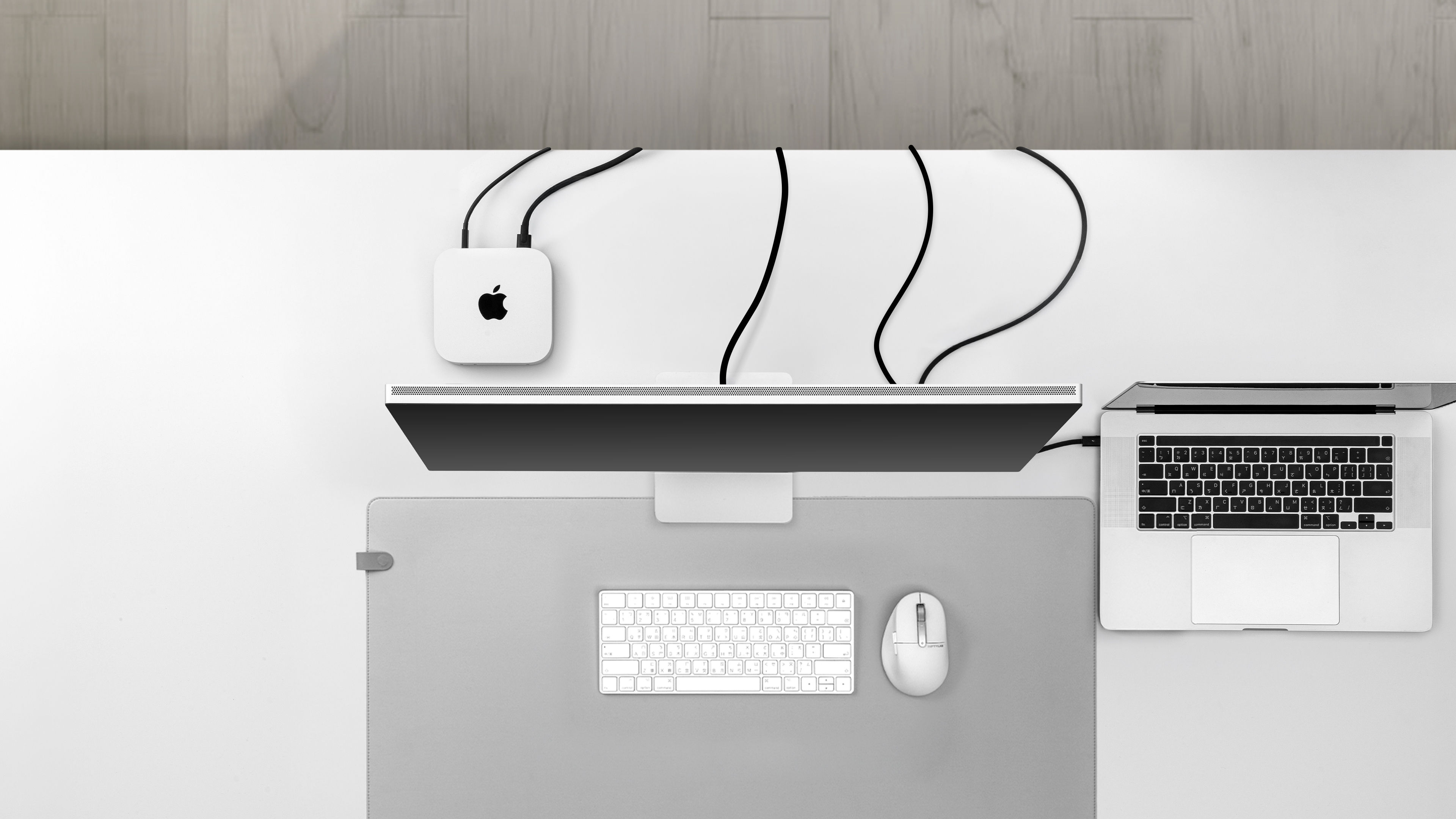 凌乱的桌面环境，Mac mini 和其他外设的裸露线缆横跨桌面，展示未使用 Studio Arm 理线方案时的状态。
