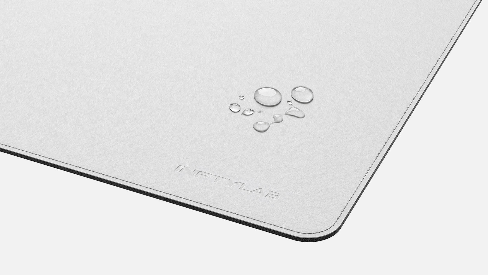 Water droplets beading on the FLOW Desk Mat surface, showing stain-resistant and water-repellent finish