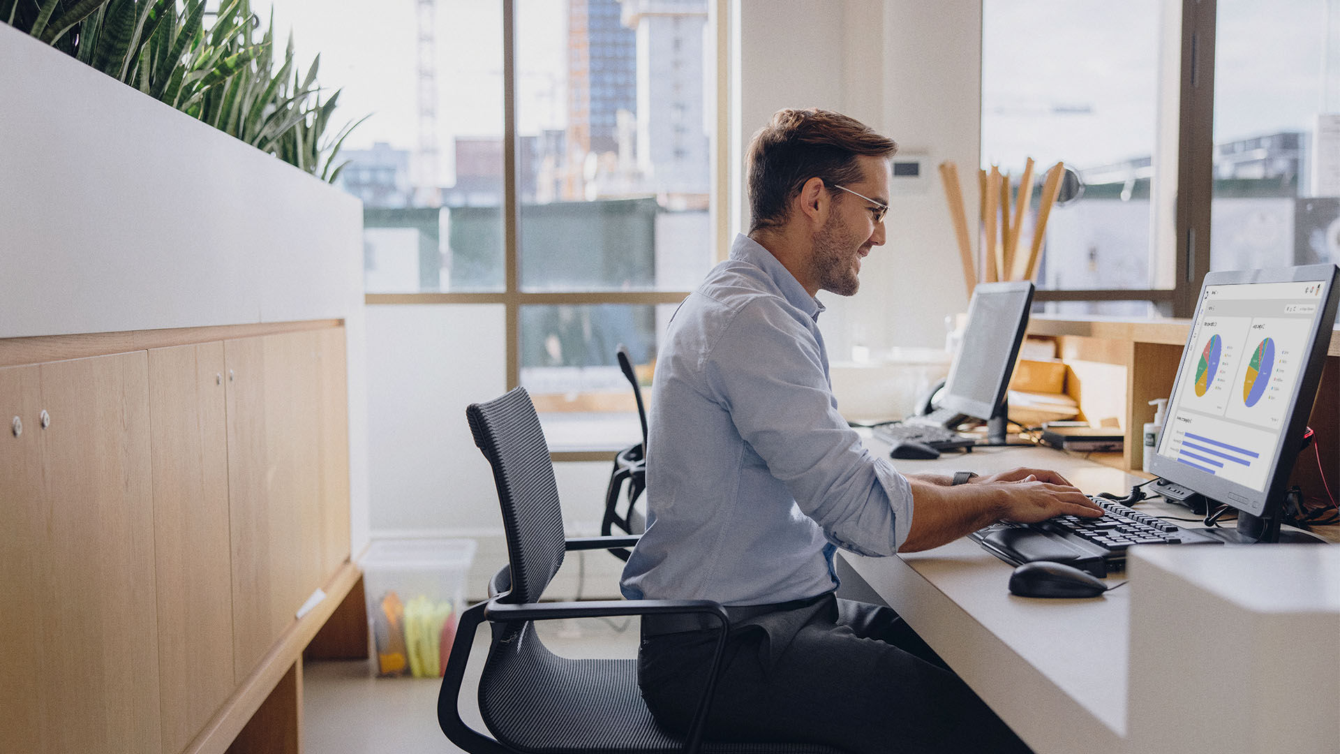 رجل يعمل كمدير تكنولوجيا المعلومات يكتب على لوحة إدارة حل إدارة الأجهزة (DMS) الموجودة بالكمبيوتر