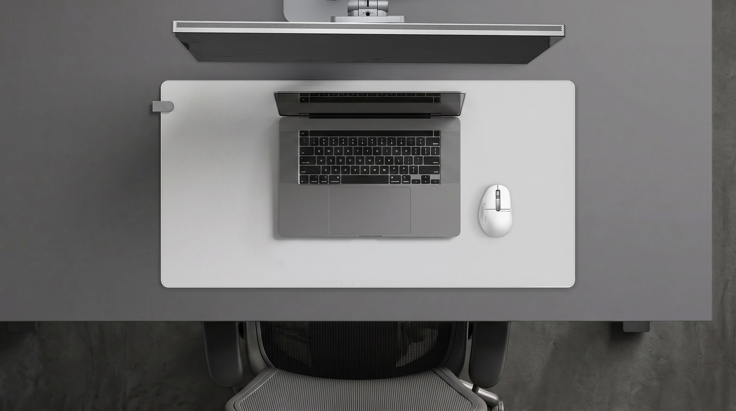 FLOW Desk Mat on a dark desk with MacBook Pro setup — laptop and mouse arranged on the mat surface
