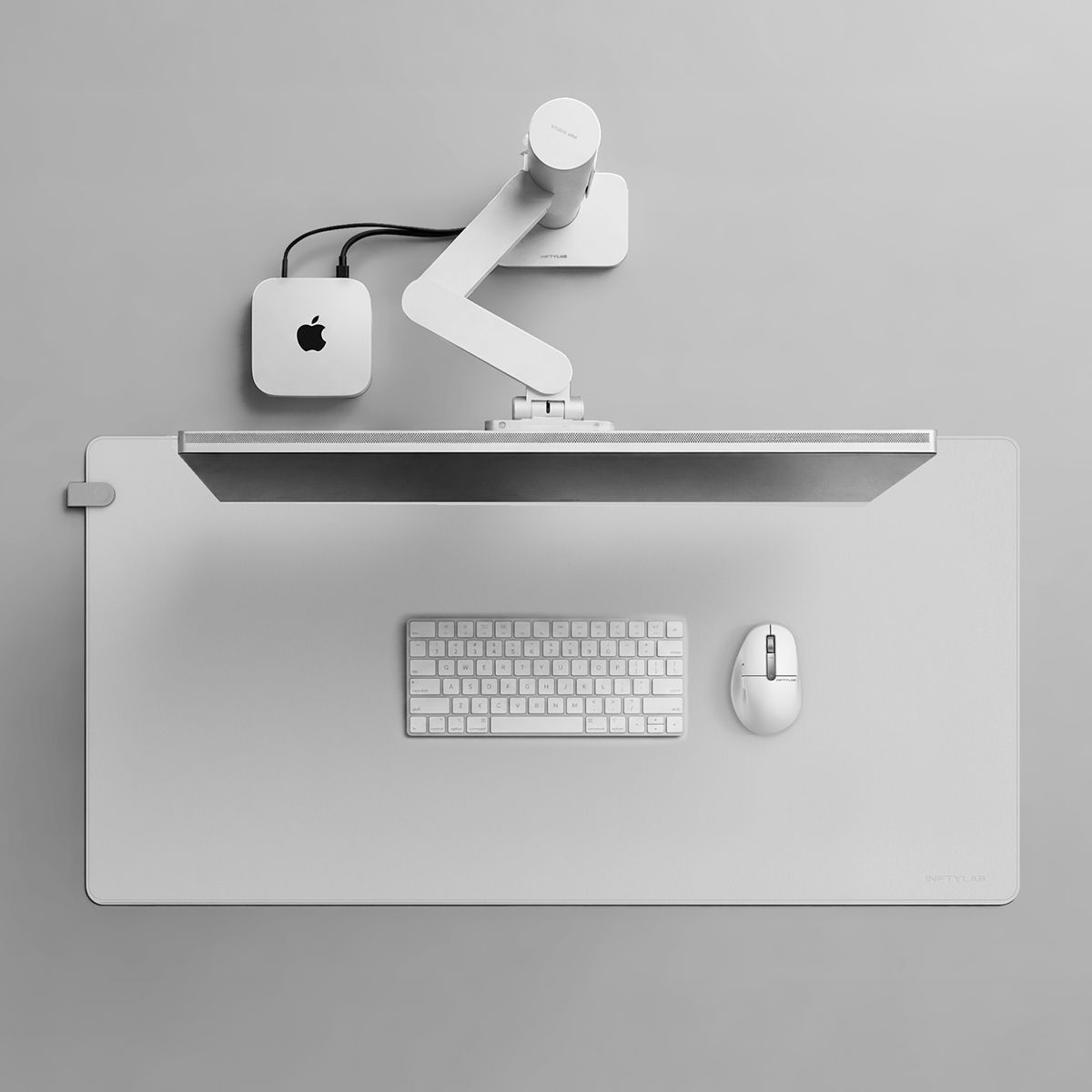 Top-down view of a complete Mac desktop setup with INFTYLAB Studio Arm, M Mouse, keyboard, and desk mat.