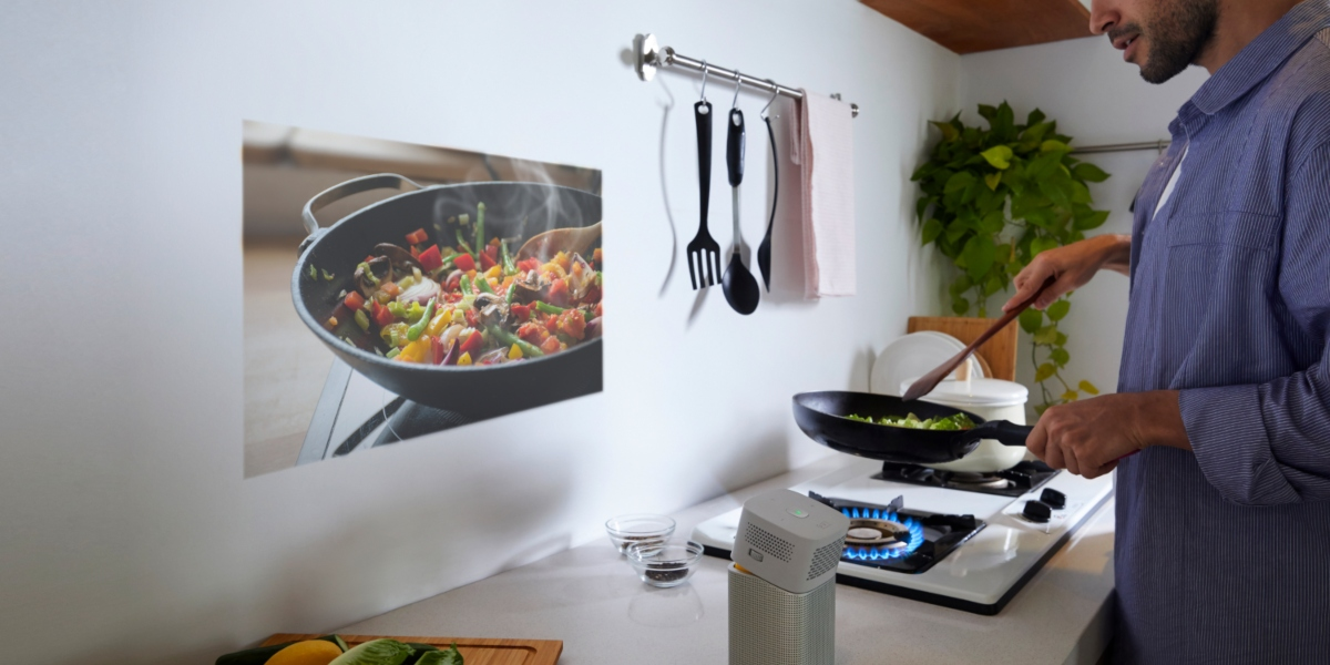 The man is cooking in the kitchen with the display of cooking show projected by portable projector GV1.