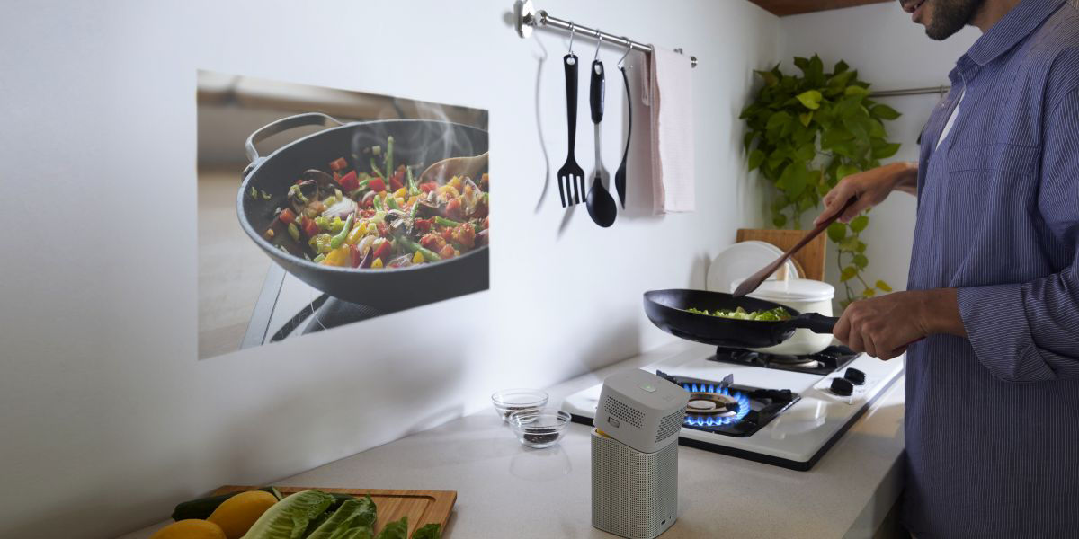 A man is cooking and using a projector.