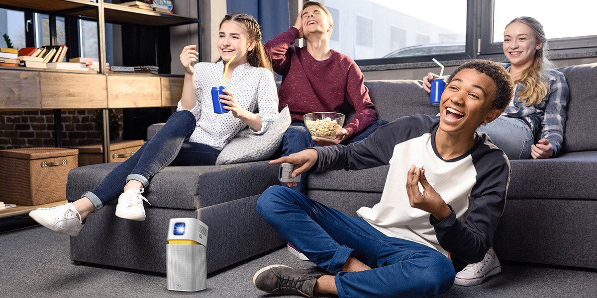 friends get together in a smaller space watching big entertainment on a portable projector.