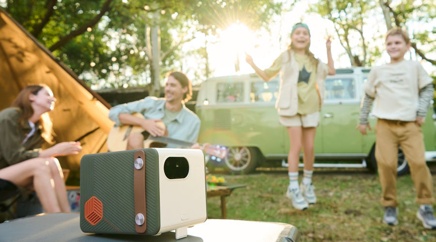 Family having a great time with a portable projector by a van