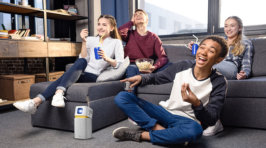 friends get together in a smaller space watching big entertainment on a portable projector.