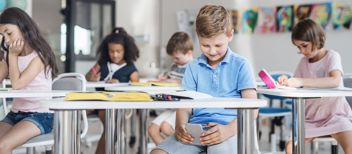 alpha generation student in a classroom, distracted during class, playing on his smartphone