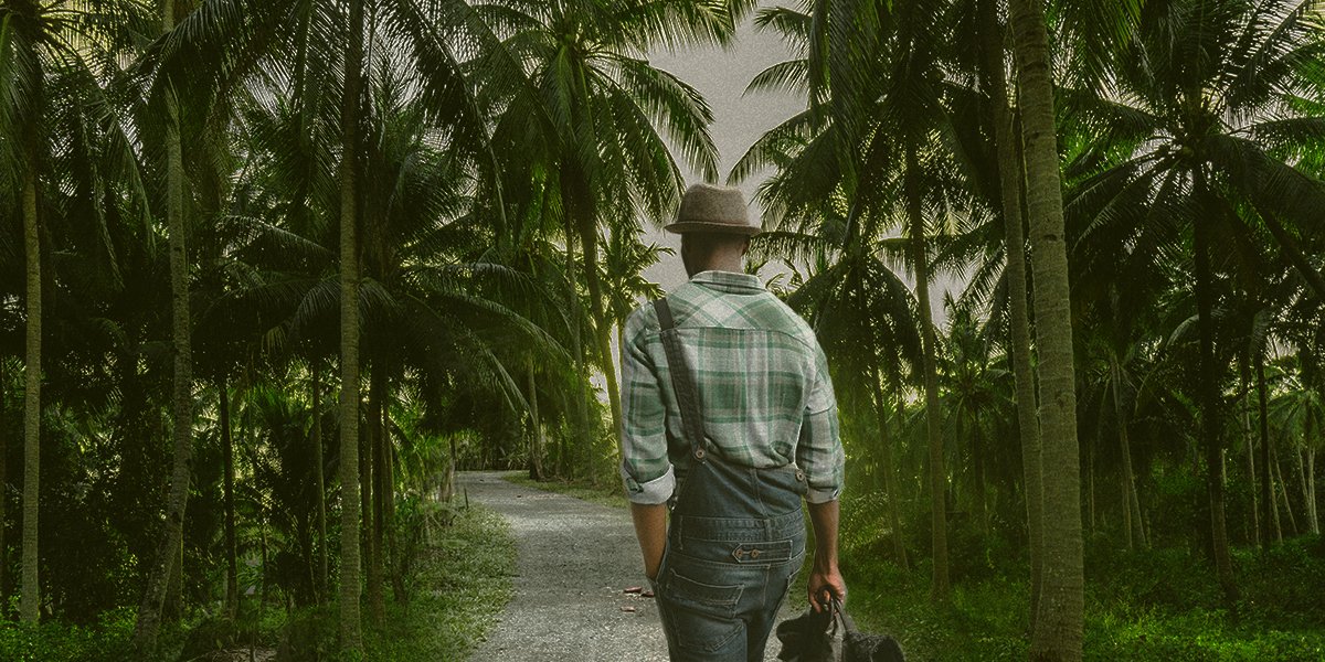A man in a hat walking in palm trees in the Philippines 