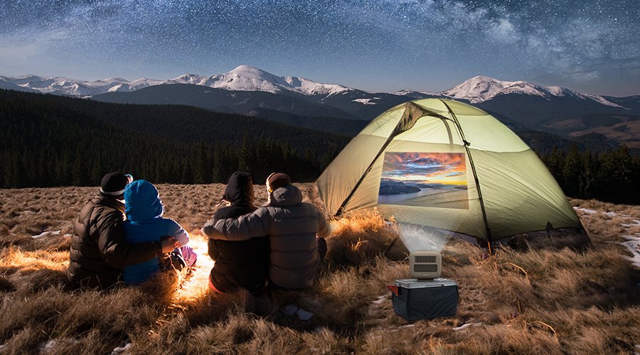 4 friends camping in the wild and watching movies under the stars with an outdoor projector