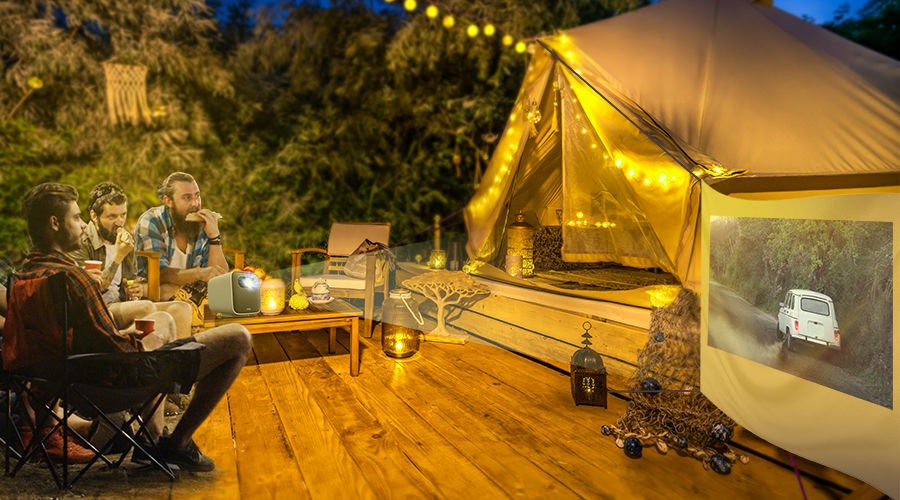 three friends get together at a glamping site watching movies on a portable projector