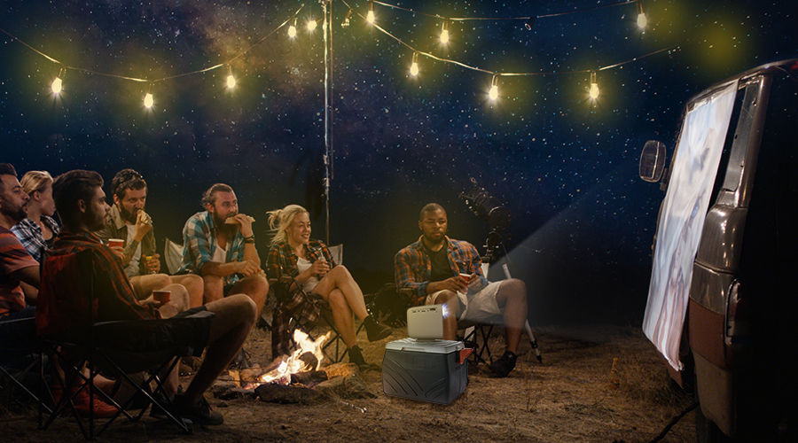 a group of friends watching outdoor cinema on camper RV with a portable projector