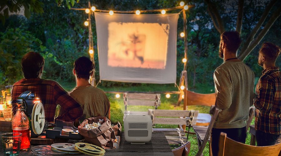 There are four friends gathering in the backyard and enjoying outdoor cinema with a portable projector GS2.