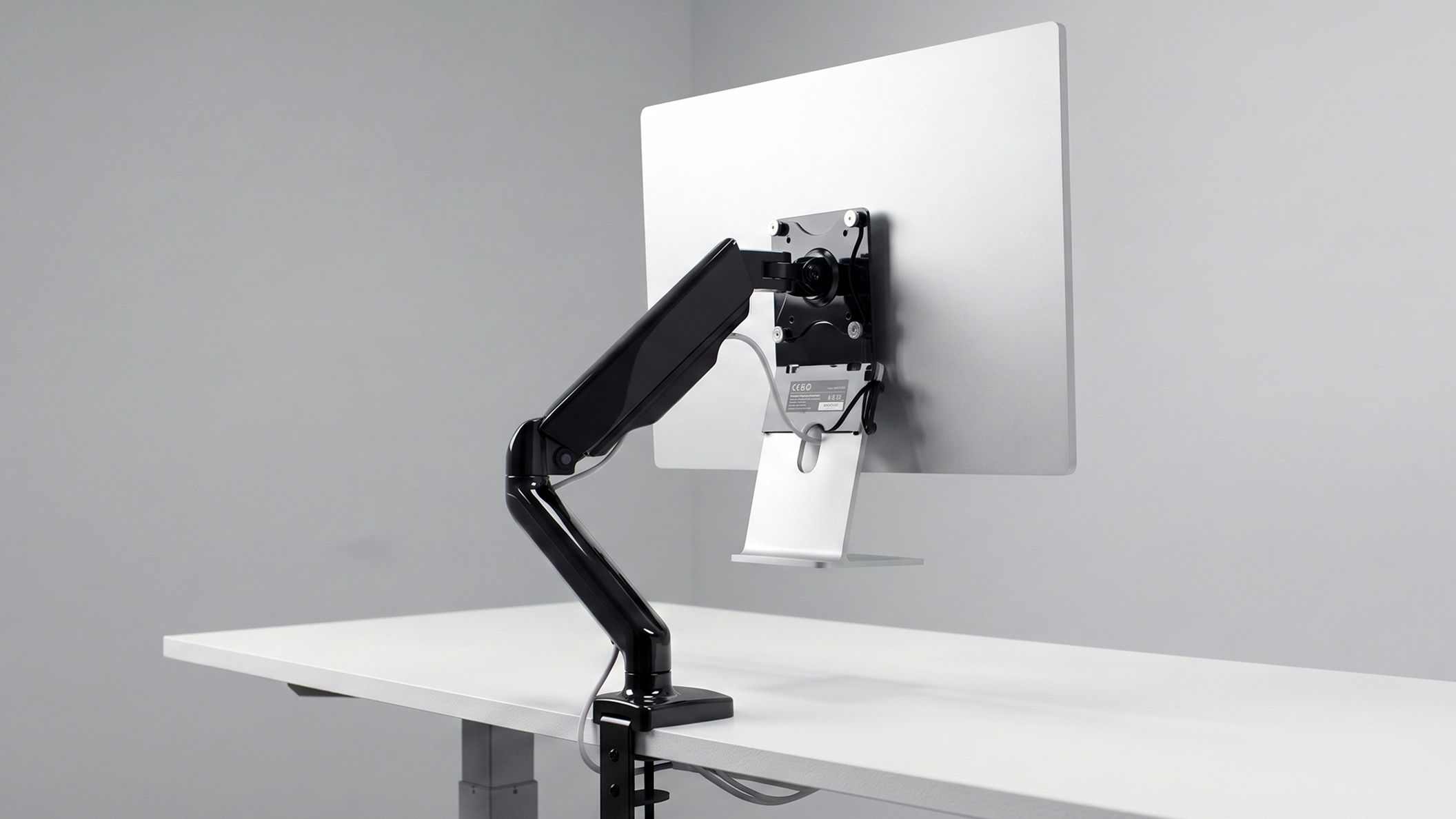 Apple Studio Display mounted on a standard monitor arm that partially covers the Apple logo and contrasts with the display's minimalist design.