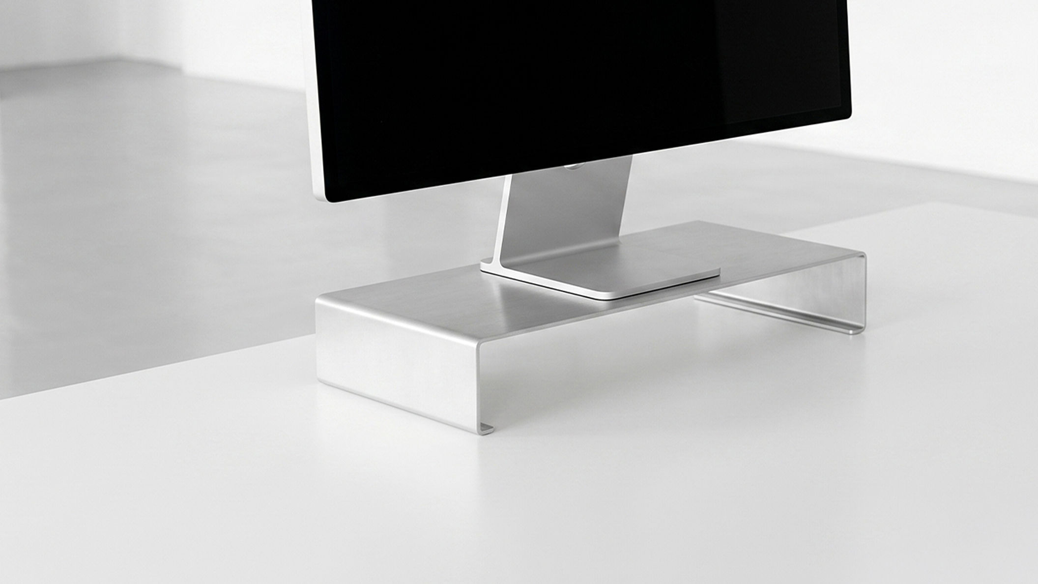 Apple Studio Display placed on a monitor riser to increase monitor height while preserving the original stand.