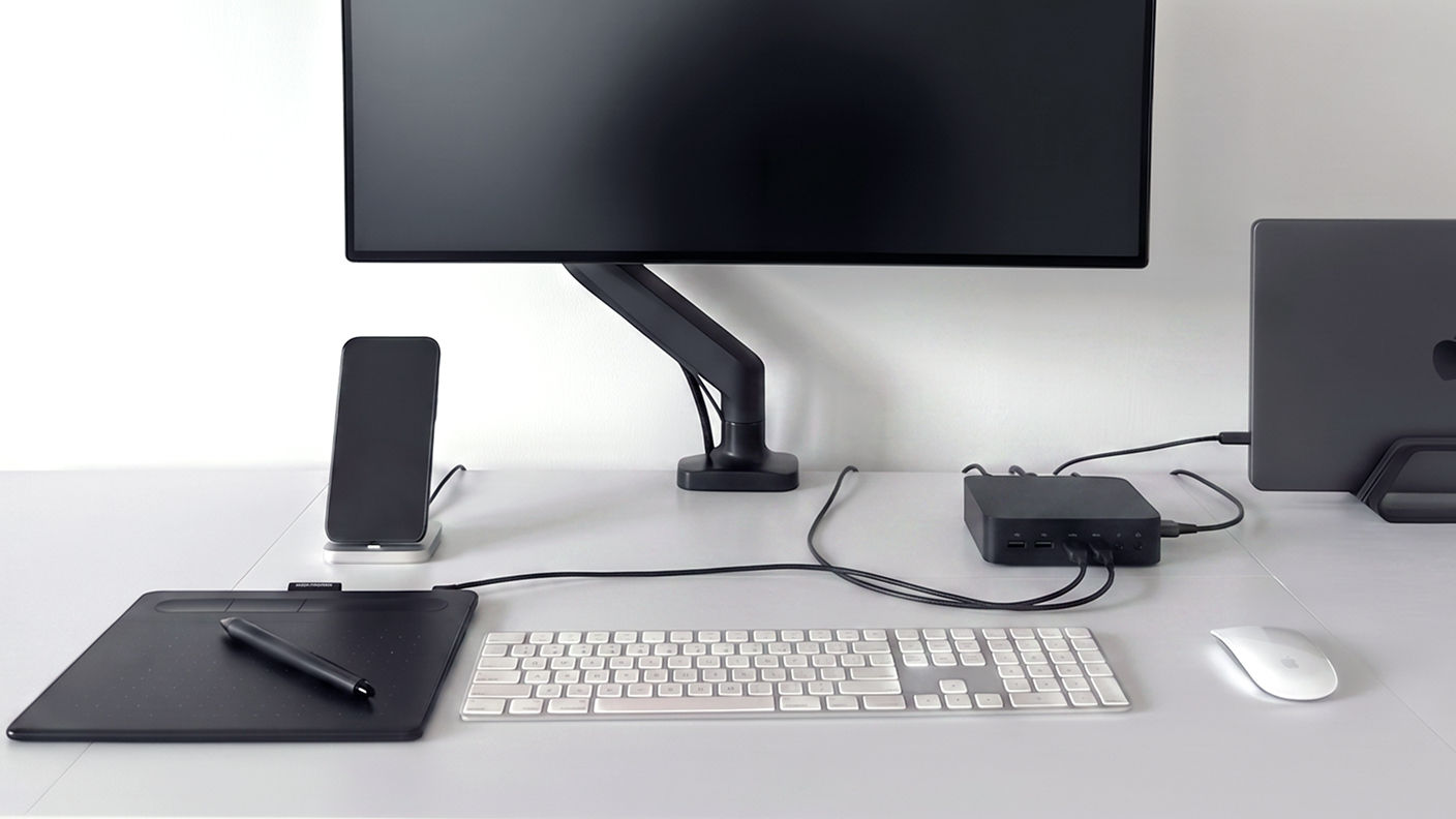 Workspace with a monitor arm, docking station, and multiple cables illustrating desktop cable clutter.