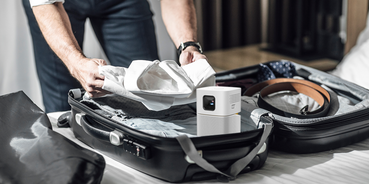 A business man packing up with a portable projector for travel