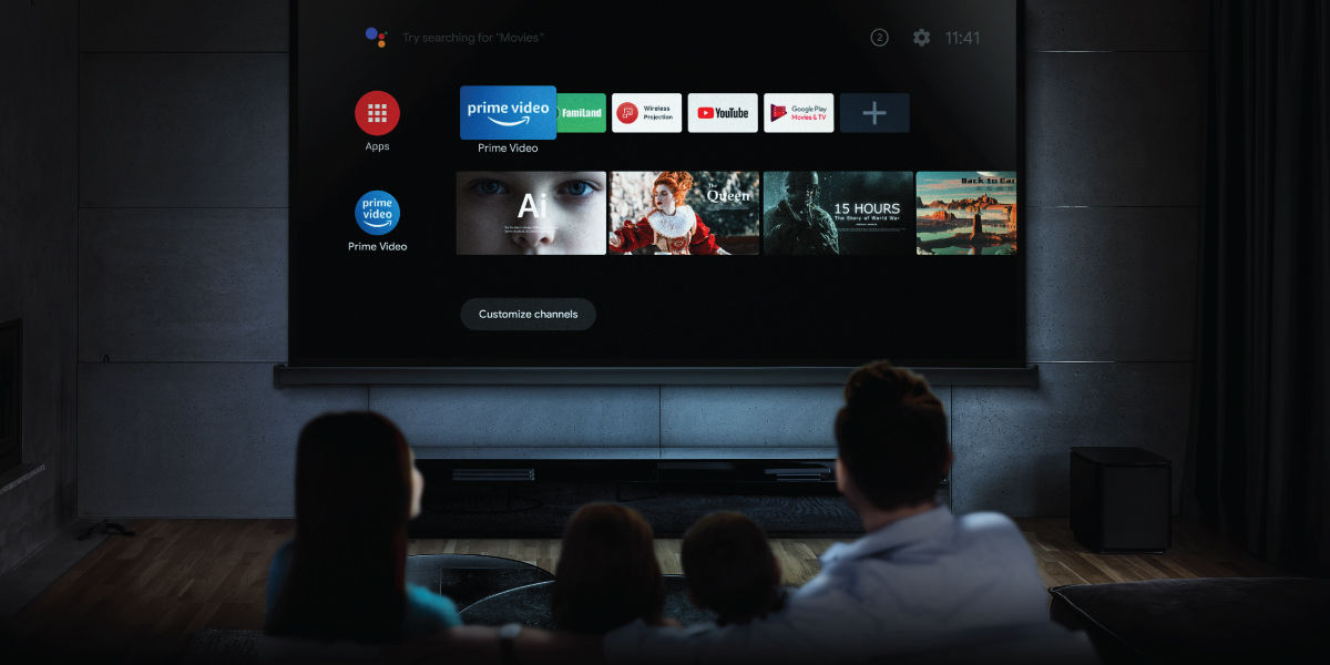 A family sitting in the living room watching on a projector with Android TV function