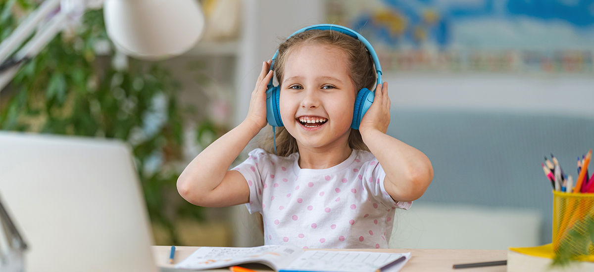 Student learning remotely from her laptop with headphones on is happy because she can hear the teacher well and can understand the content of the class better with array microphones