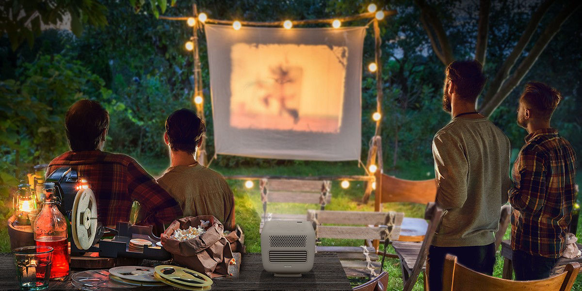 There are four friends gathering in the backyard and enjoying outdoor cinema with a portable projector GS2.