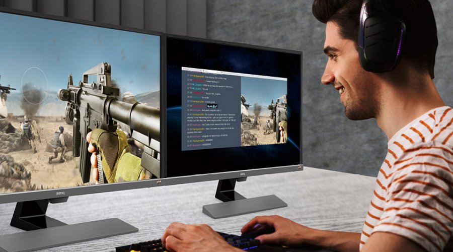 Молодой человека использует два монитора для компьютерных игр