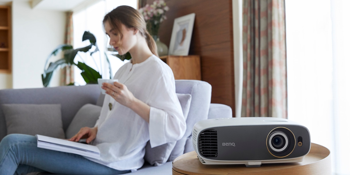 A woman is working from home while enjoying her free time with a projector for visual entertainment.