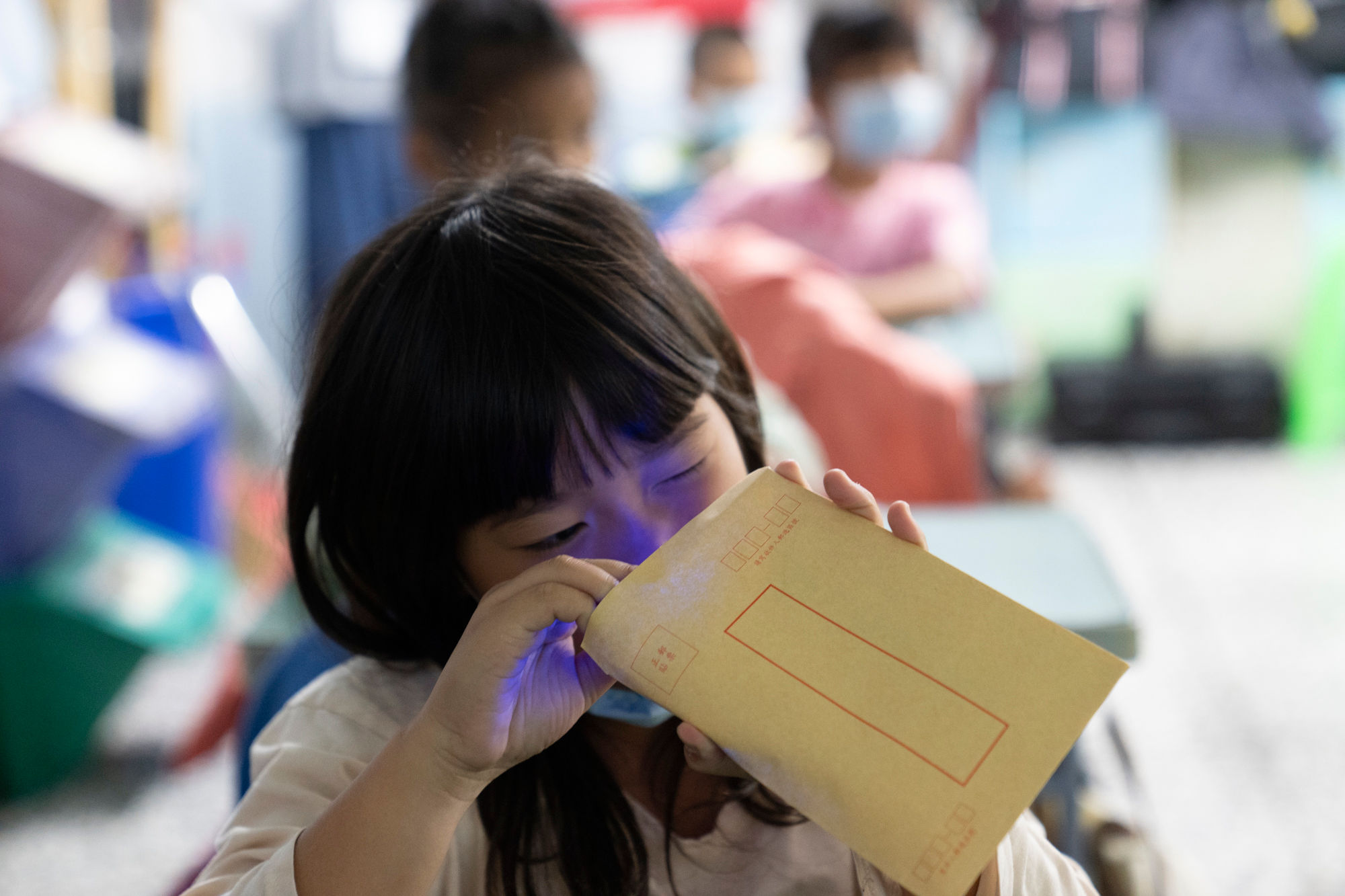 （圖說：孩子們專注地觀察信封裡的色彩密碼卡，是否因為不同色光而變色。）