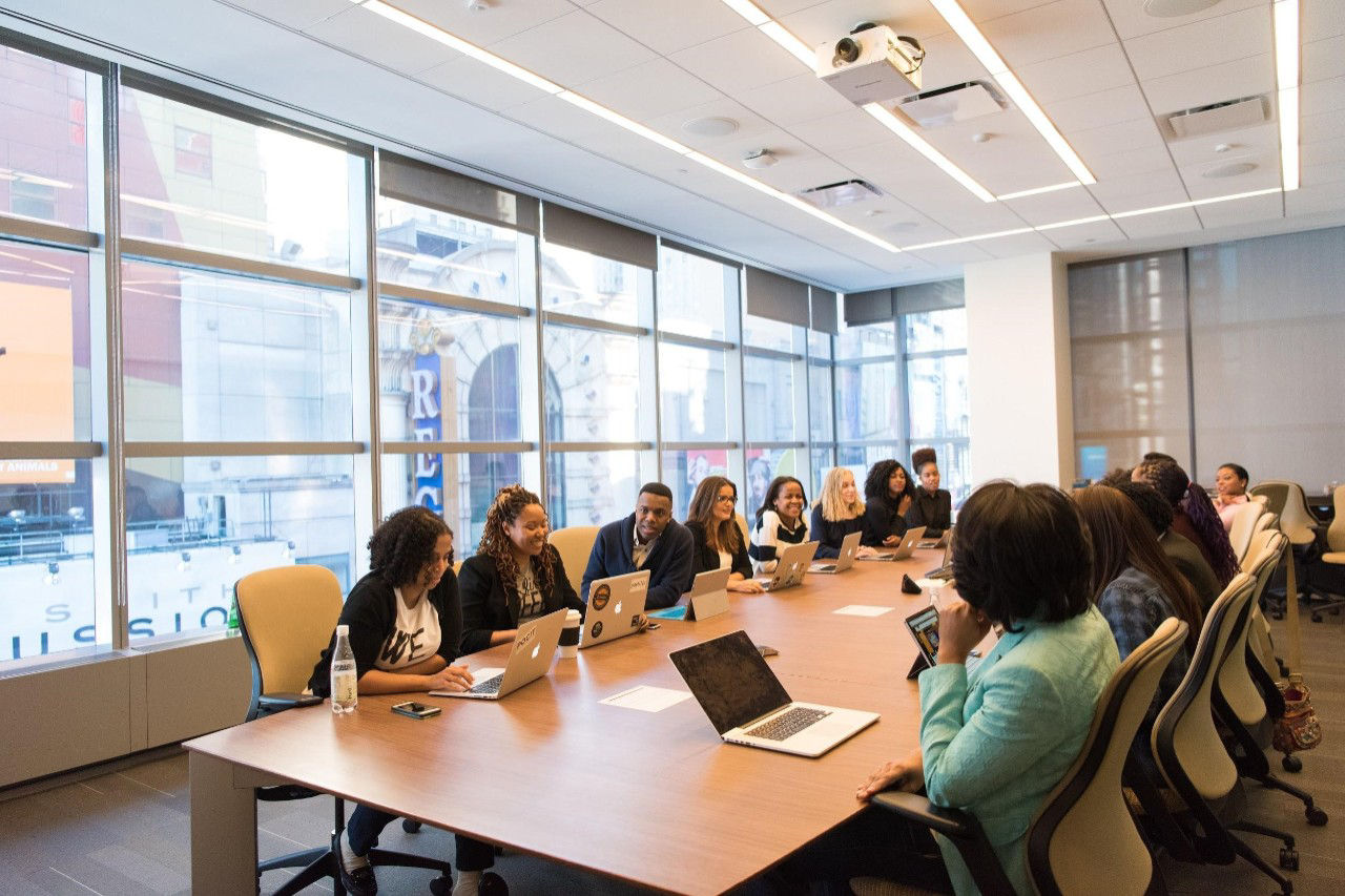 There a group of team members sharing their ideas and opinions with their own devices in the meeting room.