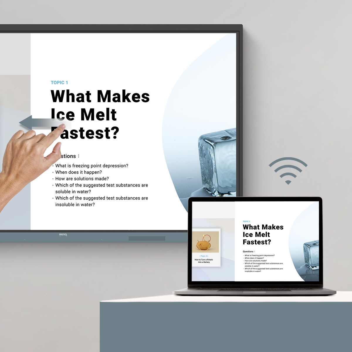 Teacher writing on interactive display over content shared from laptop 