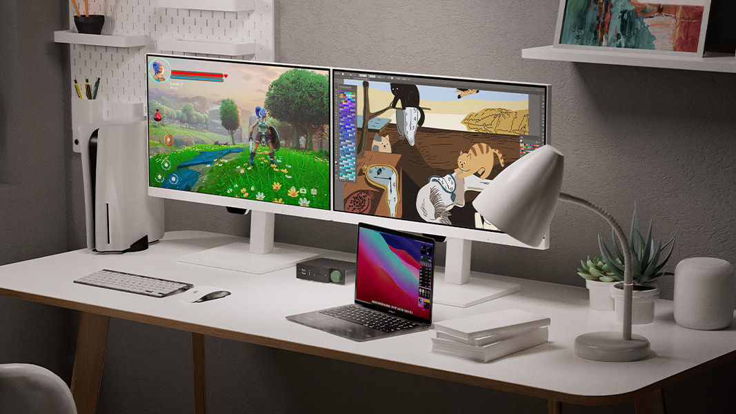 A neat and clean desktop is equipped with a docking station, connected to a MacBook and two monitors, and a PS5 is used for gaming and entertainment.