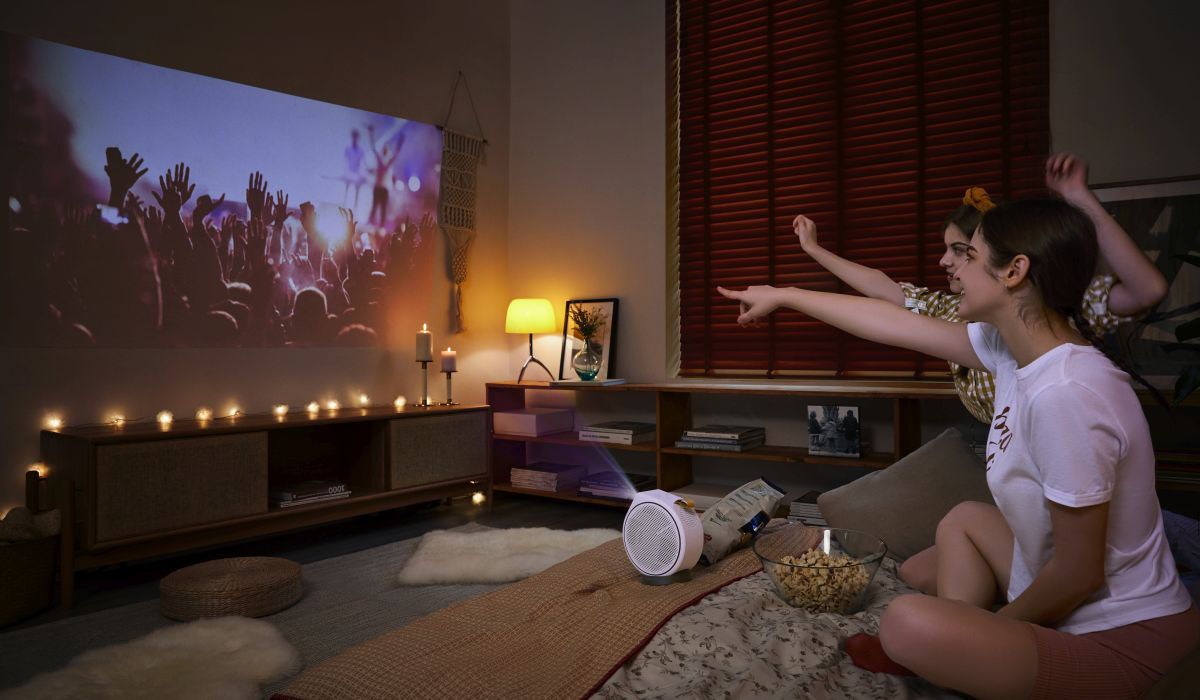 Two friends using portable projector in a dorm to watch a concert