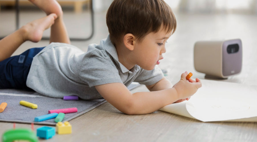 A kid drawing to a portable projector while receiving edutainment at home 