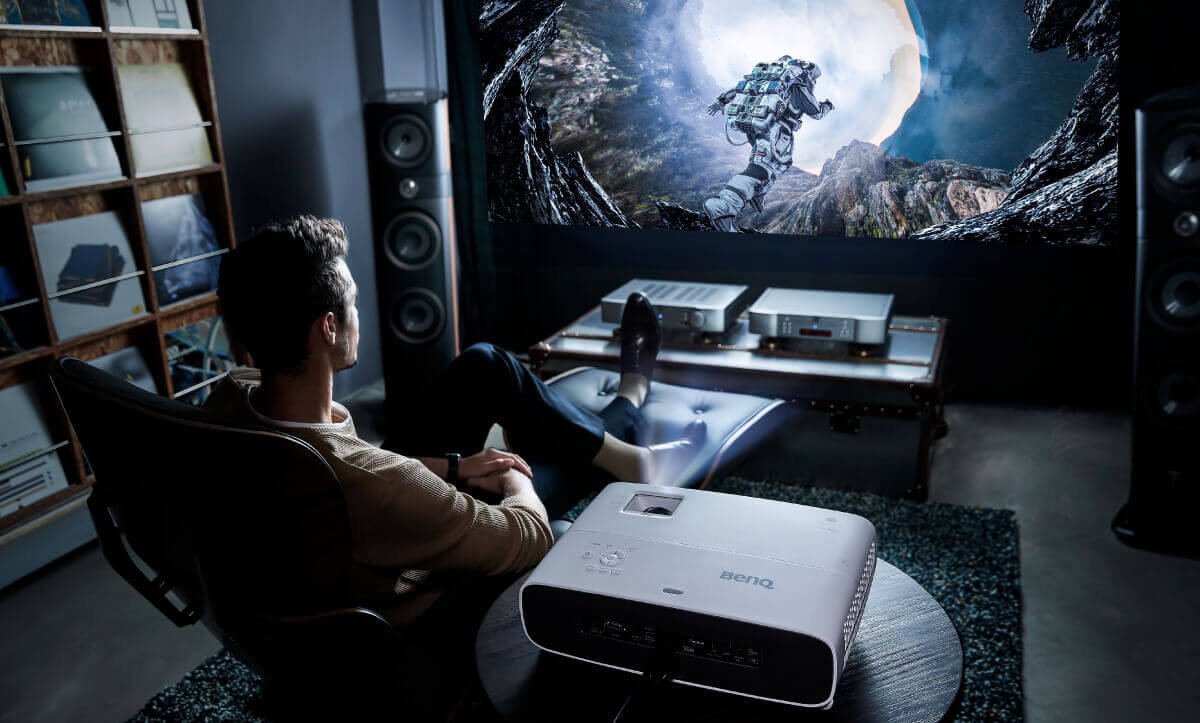 Een man kijkt naar een film die door een BenQ-beamer op het projectiescherm wordt geprojecteerd.