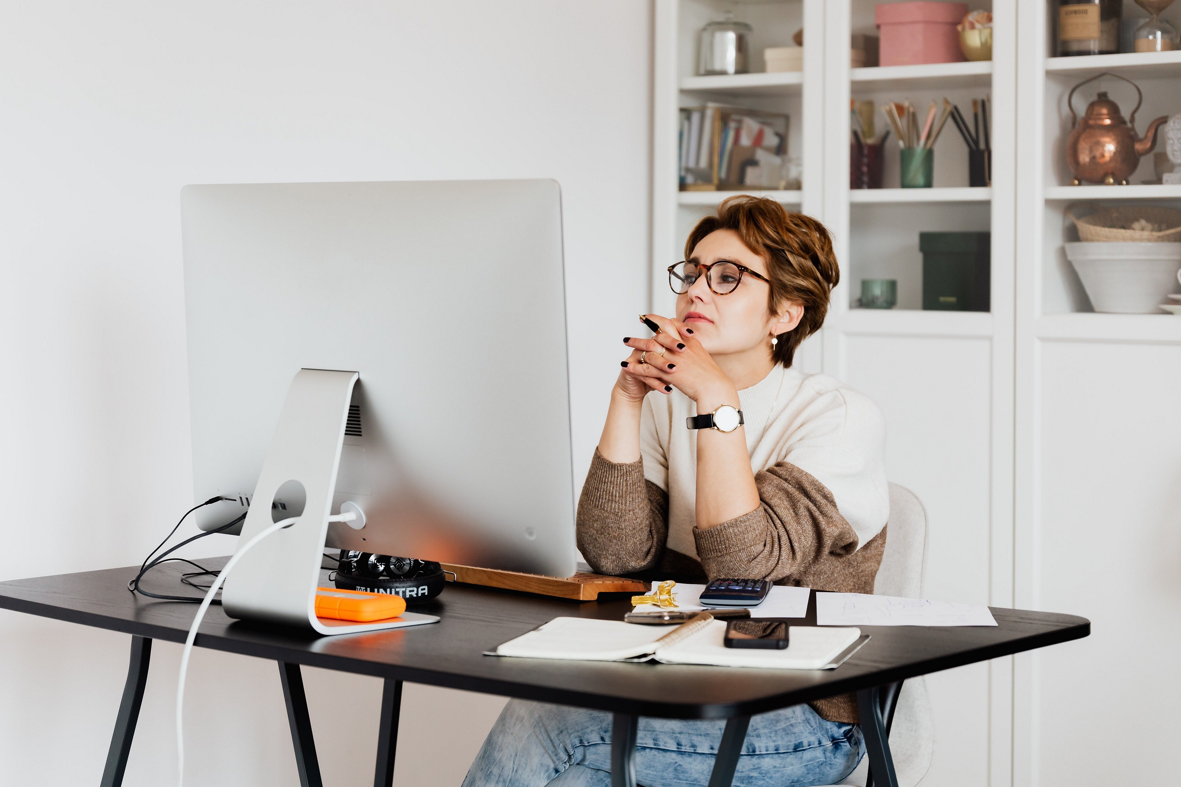 girl with glasses sitting in front of screen thinking