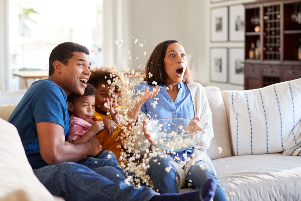 Eine Familie schaut zusammen einen Film und verschüttet vor Schreck das Popcorn