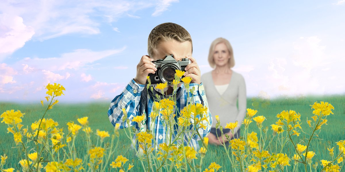 a boy taking photos of the rape flower while an older woman standing behind him and smiling
