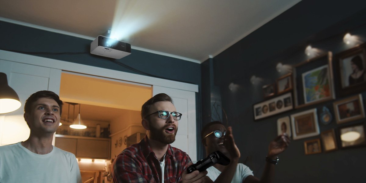 Zwei Männer spielen in einem Wohnzimmer Konsolenspiele auf einem BenQ Gaming Beamer