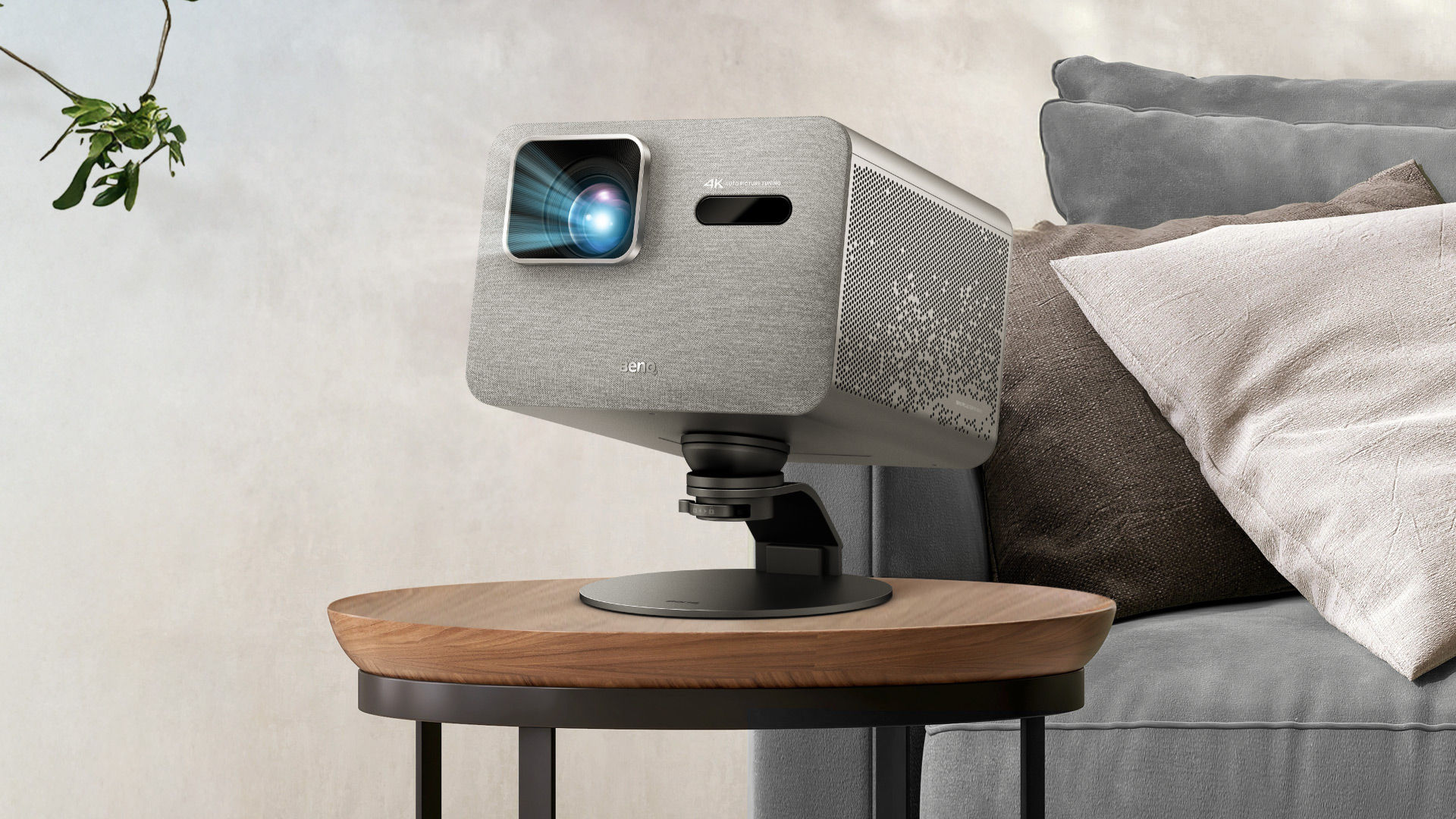 BenQ TK705i home projector on an adjustable desktop stand beside a sofa