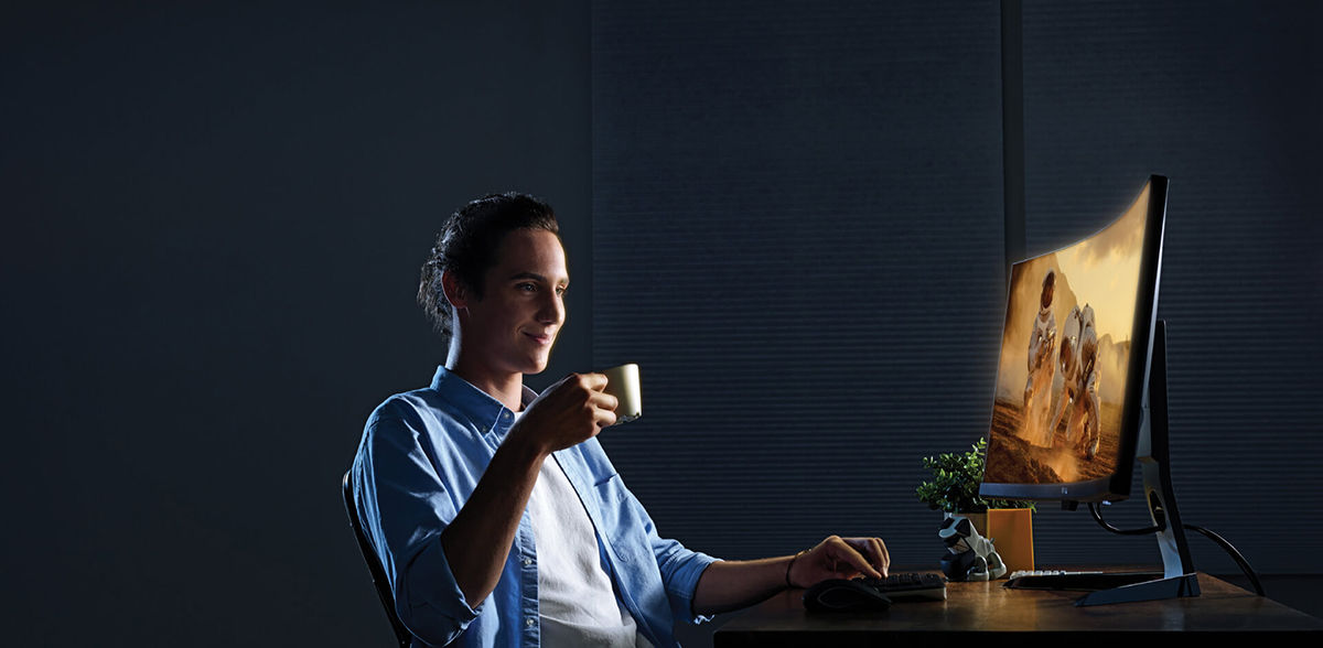Мужчина за компьютером с чашкой в руке