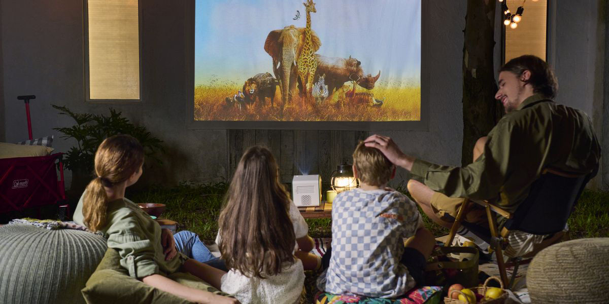 Family watching a movie outdoors in a backyard