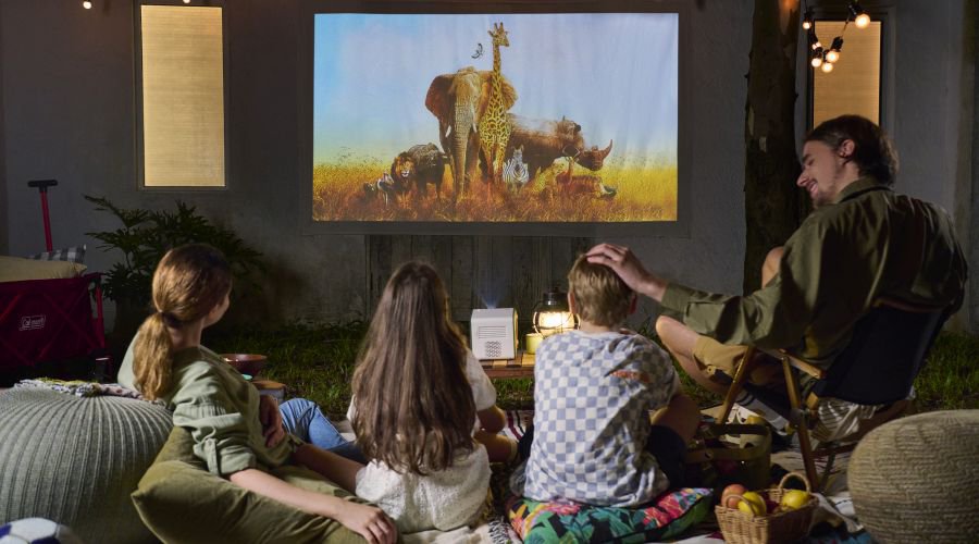 Family watching a movie outdoors in a backyard
