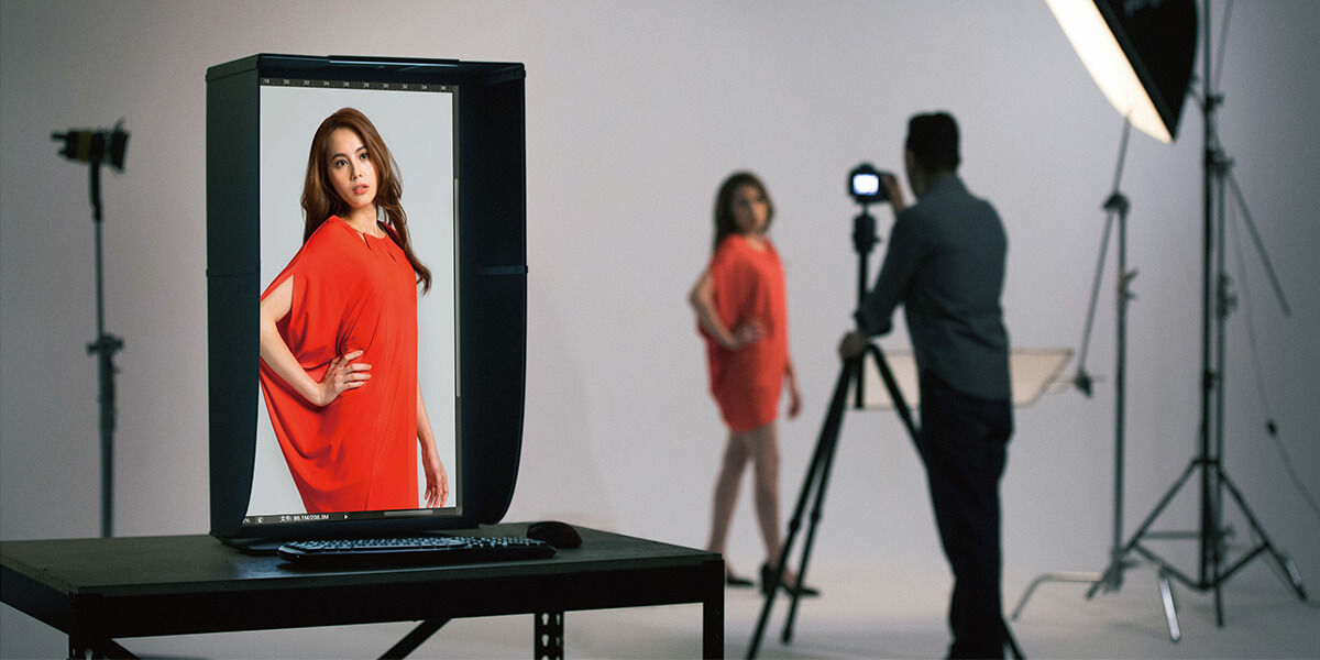 The photographer is taking photos with the camera and the monitor that can pivot 90 degrees and comes with a shading hood in the studio.