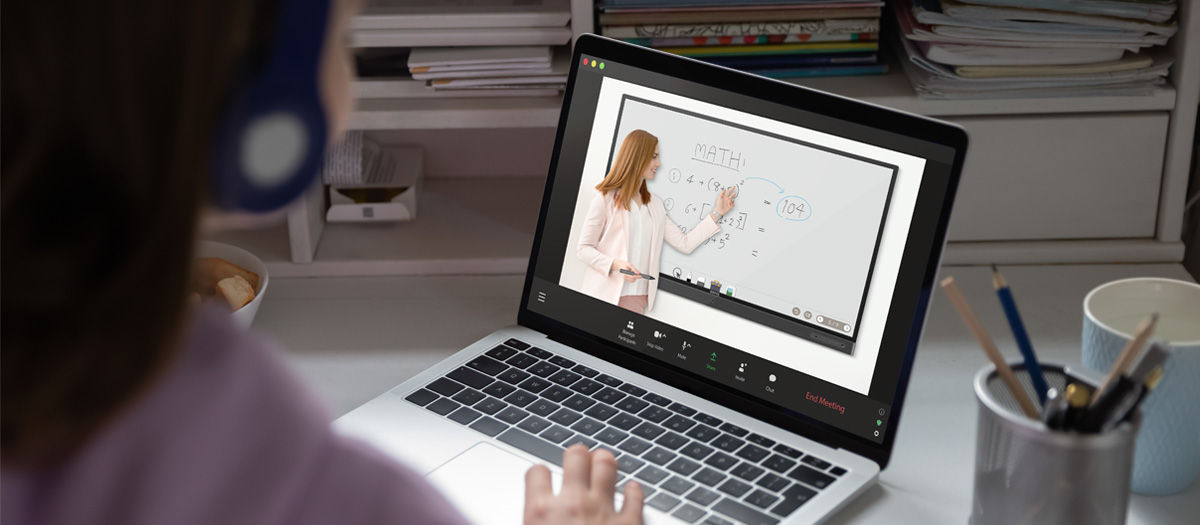 student at home, wearing headphones, watching a remote math class where the teacher uses EZWrite on BenQ Interacive Board