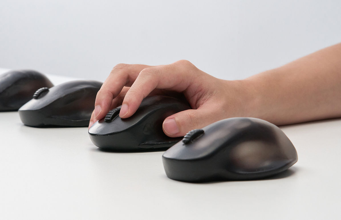 Hand testing different mouse prototypes to analyze contact area and pressure during grip.